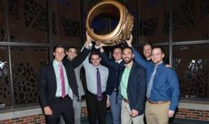 Several students hold a large replica of the HSU class ring.